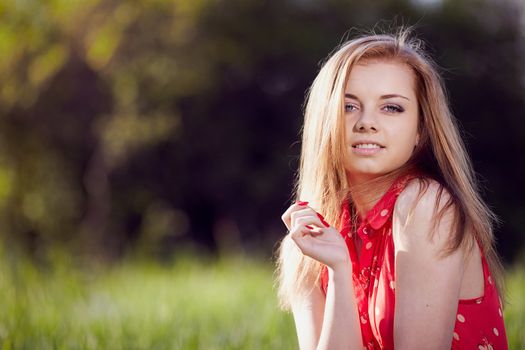 Beautiful woman in a red dress on a background of spring green.