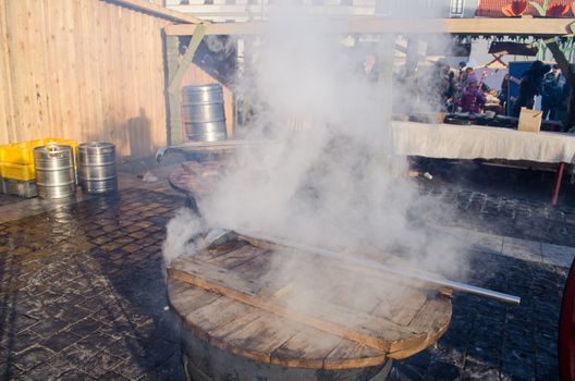 people buy hot drink wine boil in huge pots and smoke vapour rise in spring outside market fair.