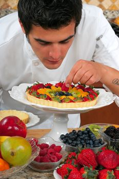 Young handsome chef making fruit tarts