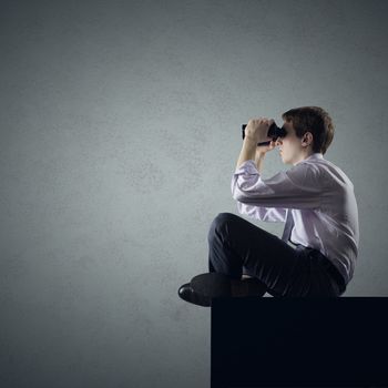 Young business man or student looking through binoculars