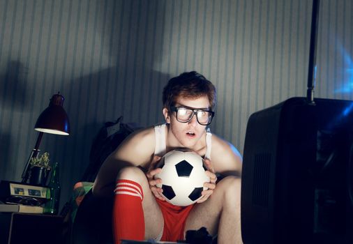 Young man soccer fanatic watching soccer match in television