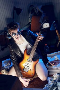 Excited boy playing electric guitar in front of the television