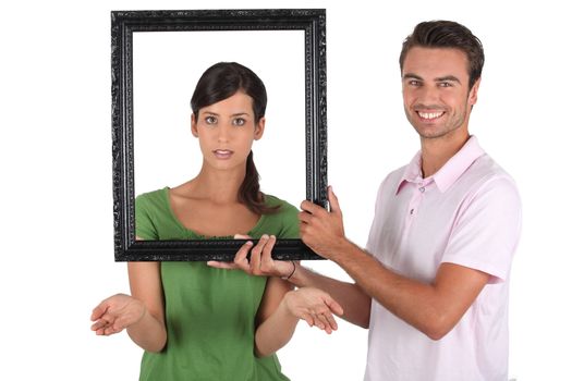 Playful couple stood with empty picture frame