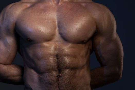 Photo of naked muscular man's torso on a dark background