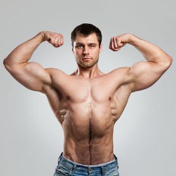 Handsome muscular guy with naked torso isolater over a grey background