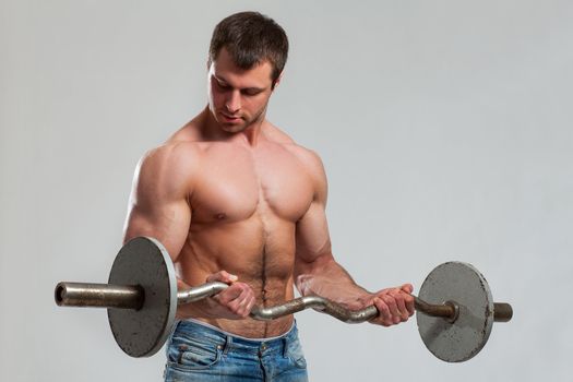 Handsome guy working out with dumbbells isolated over grey background