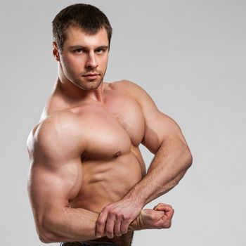 Handsome muscular guy with naked torso isolater over a grey background