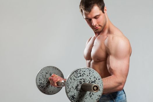 Handsome guy working out with dumbbells isolated over grey background