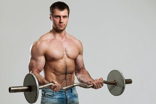 Handsome guy working out with dumbbells isolated over grey background