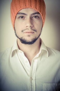 young modern stylish man with orange cap on vignetting background
