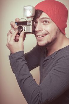 young stylish man holding old camera on vignetting background
