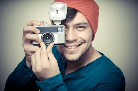 young stylish man holding old camera on vignetting background
