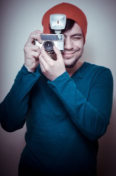 young stylish man holding old camera on vignetting background
