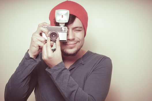 young stylish man holding old camera on vignetting background