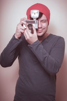 young stylish man holding old camera on vignetting background