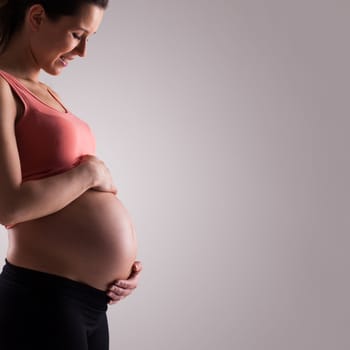 Beautiful pregnant woman isolated over grey background