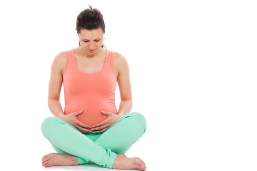 Beautiful pregnant woman sitting; isolated over white background