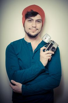 young stylish man holding old camera on vignetting background