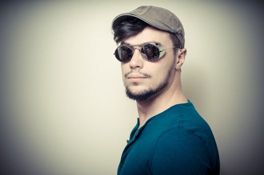 young modern stylish man with cap on vignetting background