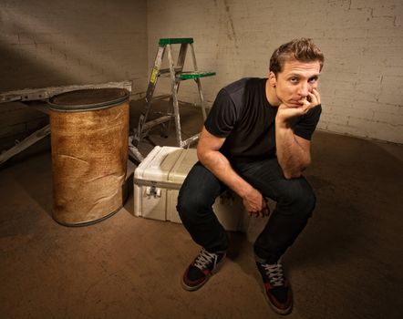 Bored laborer sitting on cooler in unfinished basement