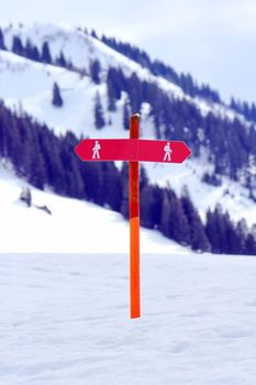 Two red signs for walkers in the snowy mountain