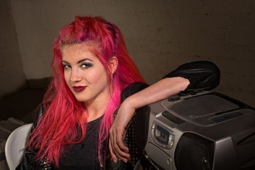 Cute grinning girl with pink hair leaning on radio