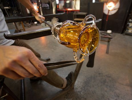 Close up of pliers on hot vase in glass factory