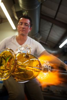 Latino glass artist sculpting glass vase with blowtorch