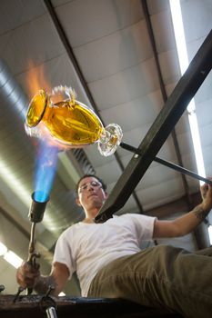 Industrial artist creating a yellow glass vase
