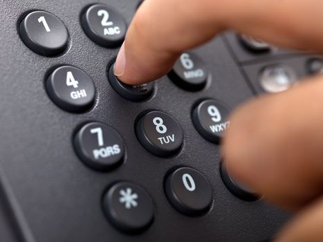 Close-up cropped image of a person dialing landline phone.