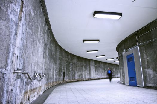 A nice grunge corridor with a blue door. It was a very dark and weird place. This passage is part of a Montreal metro station. This is how to transit from a metro to an other (to change line). Only one women walking in this picture.