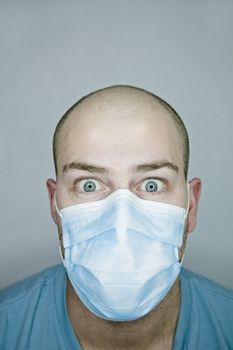 Young doctor with bald head wearing a mask and on a gray background (in studio)