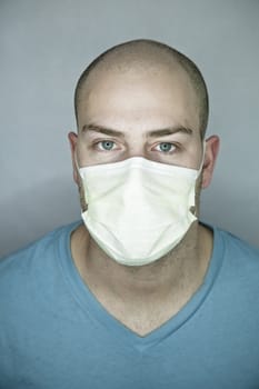 Young doctor with bald head wearing a mask and on a gray background (in studio)