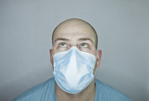 Young doctor with bald head wearing a mask and on a gray background (in studio)