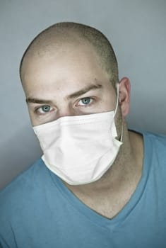 Young doctor with bald head wearing a mask and on a gray background (in studio)
