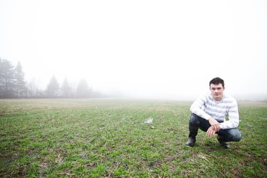 Young adult in a foggy and wet field