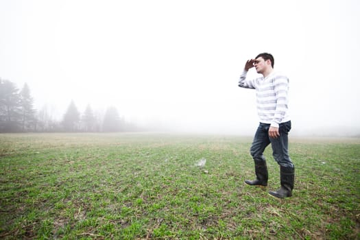 Young adult in a foggy and wet field