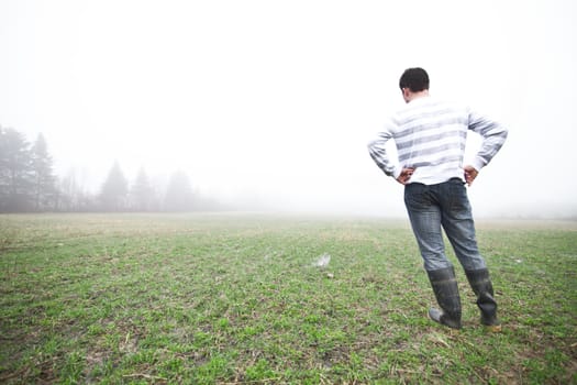 Young adult in a foggy and wet field