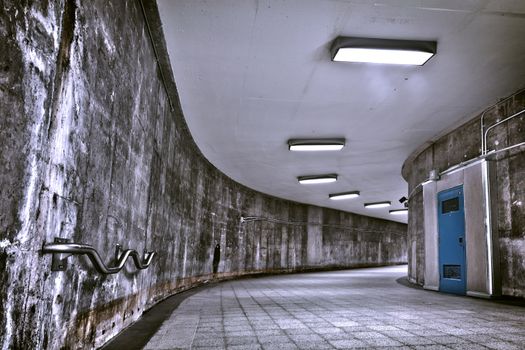 A nice grunge corridor with a blue door. This is a HDR image to get as much details as possible. It was a very dark and weird place. This passage is part of a Montreal metro station. This is how to transit from a metro to an other (to change line)