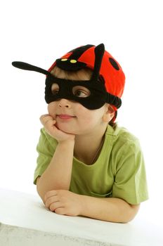 Little Boy in Ladybug Mask and Hat Leaning on Hands White Surface isolated on white background