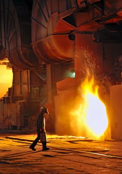 A steel worker takes a sample from oven