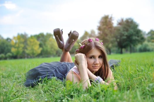 Beautiful young girl with a wreath lying in the grass
