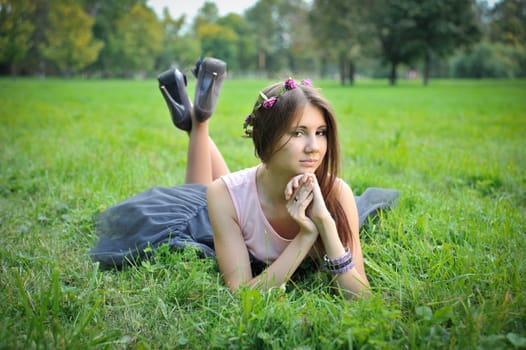 Beautiful young girl with a wreath lying in the grass
