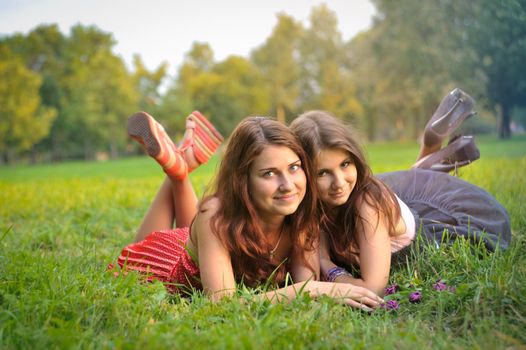 Funny 2 women lie on the grass in the summer