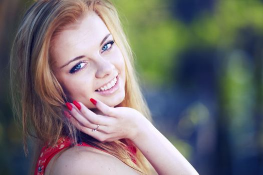 Beautiful woman in a red dress on a background of the spring woods and lakes