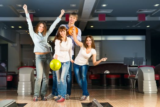 Group of young friends playing bowling, spending time with friends