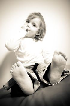 Close up of a barefoot toddler aged little girl in sepia tone. Shallow depth of field with sharpest focus on the feet and toes.