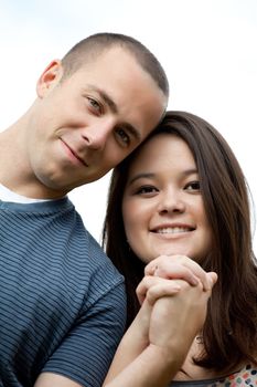 Young happy couple holding hands and showing the diamond engagement ring.  Shallow depth of field with strongest focus on the ring.