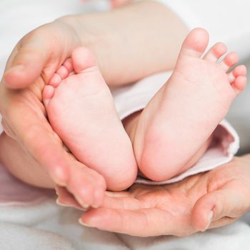 Mother's hands carefully keeping baby's feet with tenderness