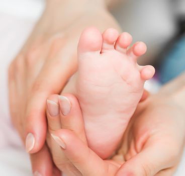 Mother's hands carefully keeping baby's foot
